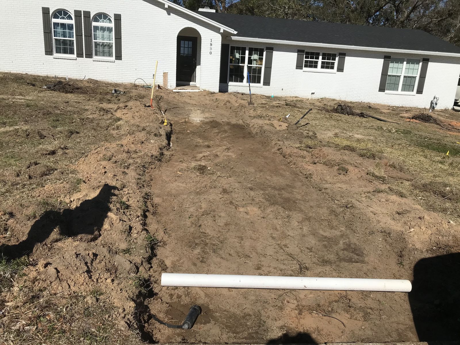 Before: bare dirt leading to the front door, with a length of PVC pipe on the ground
